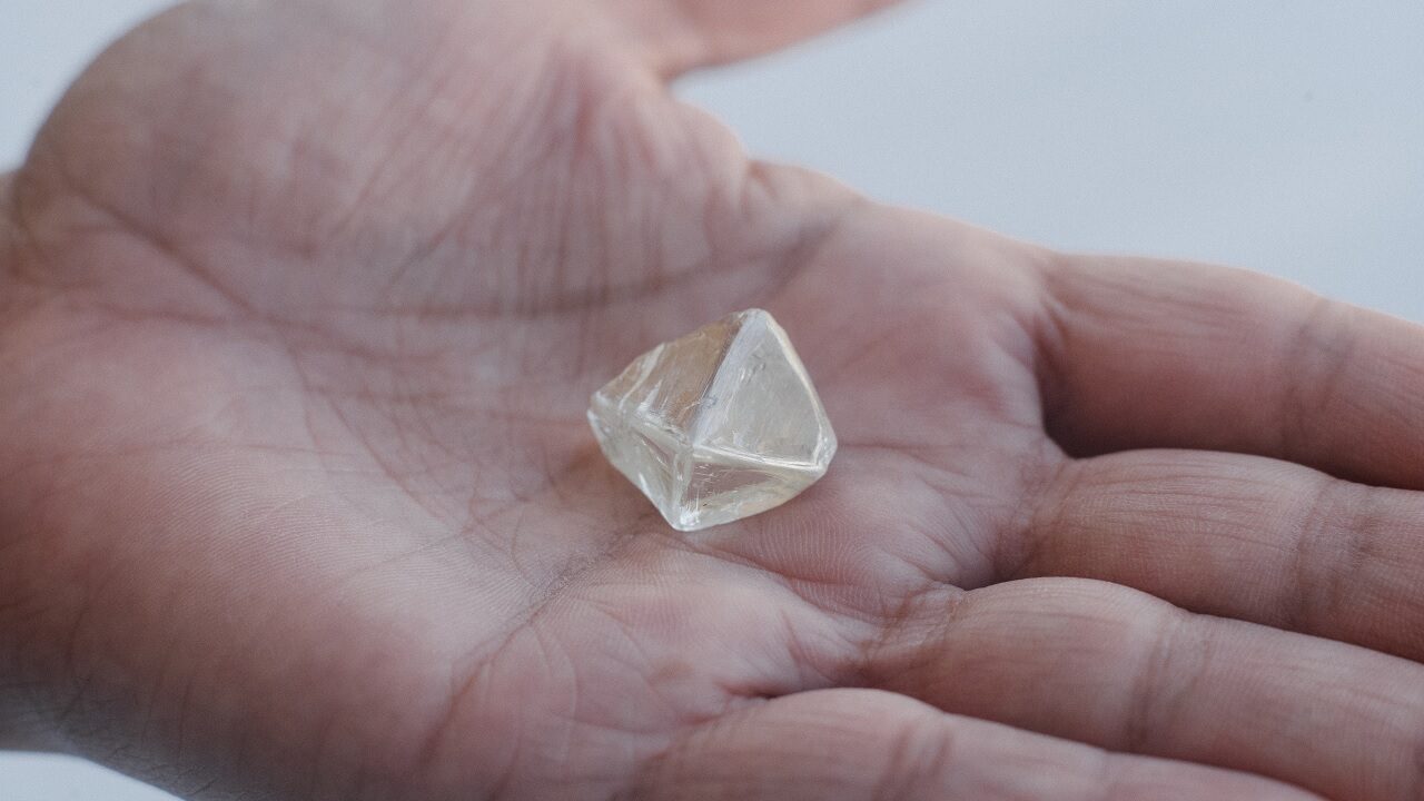 Employee holding rough diamond in palm of hand, Kimberley, DBSSSA Building, Kimberley, South Africa credit Ben Perry slash Armoury Films slash De Beers 1280 used 020123