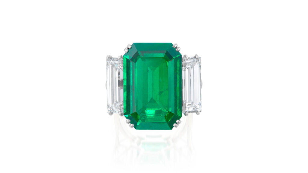 Colombian emerald between rectangular step-cut diamond ring at Phillips image