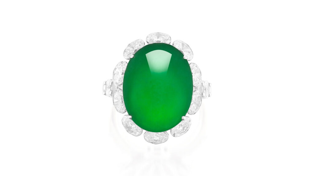 A ring centering a translucent oval jadeite cabochon in an oval-diamond surround and with brilliant-cut diamond shoulders image