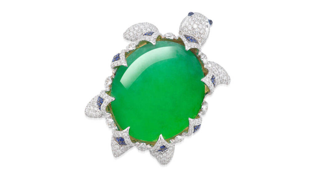 This piece is designed as a sea turtle. An oval, light-green translucent jadeite cabochon constitutes its body, with a brilliant-cut diamond and circular-cut sapphire surround and two sapphires as eyes image