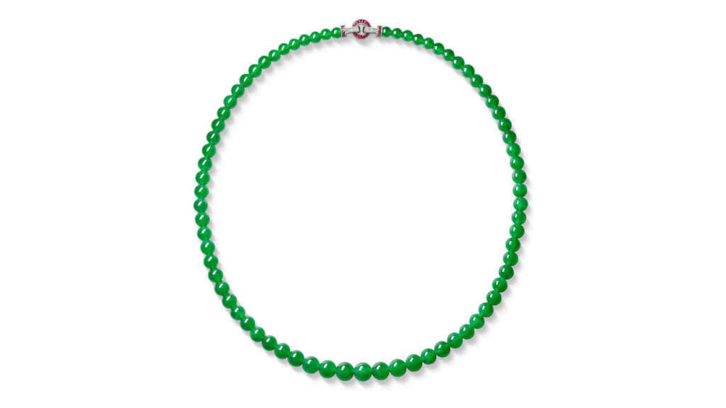 A jadeite necklace featuring 73 graduated highly translucent vivid-green beads, with a clasp boasting calibré-cut rubies and diamonds at Sotheby's image