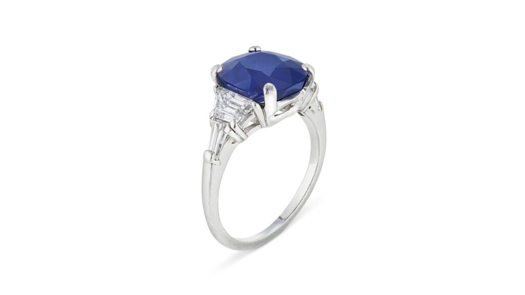 A ring centering a cushion mixed-cut, 4.81-carat Kashmir sapphire between trapezoid-shaped diamonds at Christie's image