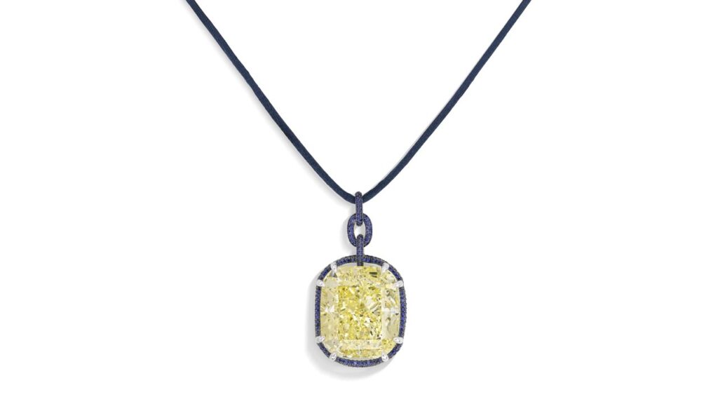 A pendant bearing a cushion-shaped, 100.40-carat, fancy-intense-yellow, SI2 diamond within a border of round sapphires at Christie's image