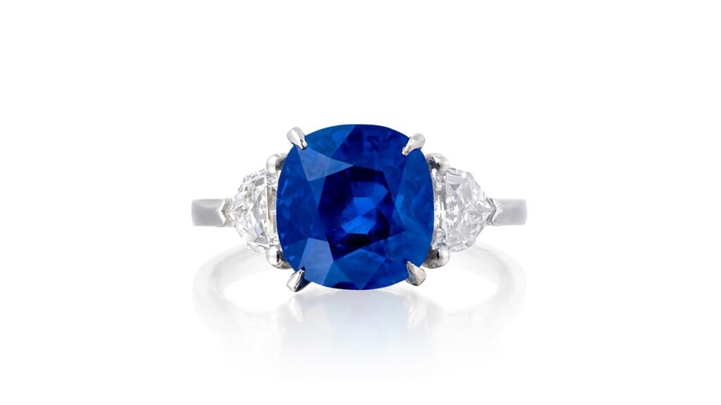 A ring features a cushion-shaped, 6.07-carat Burmese sapphire between two shield-shaped diamonds at Phillips image