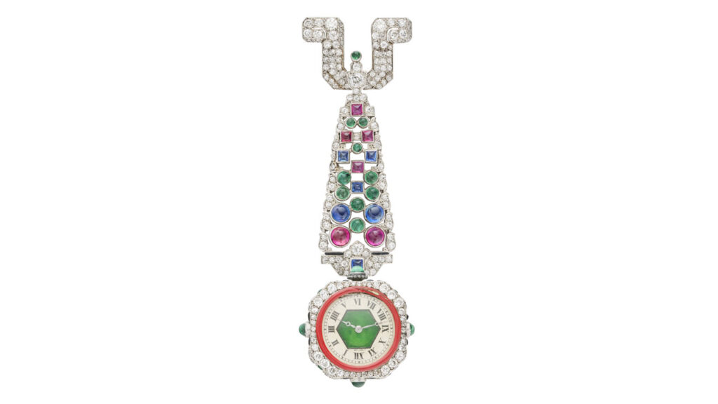 An Art Deco-designed Cartier piece from around 1925 features a watch face in a round-diamond surround, suspended from old- and single-cut diamonds, round and sugarloaf cabochon sapphires, rubies, emeralds, ring-shaped pierced emerald, red enamel, plaque and sugarloaf cabochon onyx Christie's image