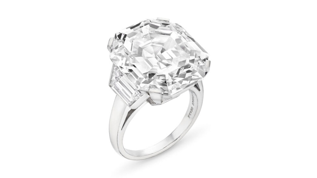 This Cartier ring bears a cut-cornered rectangular step-cut, 23.03-carat, D, VVS2 diamond, between a pair of trapezoid-shaped diamonds at Christie's image