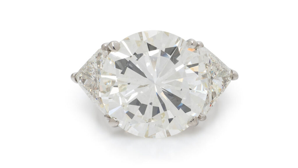 A round,12.32-carat, L, VS2 diamond is the highlight of this ring, sitting between a pair of trillion-cut diamonds at Freeman's image