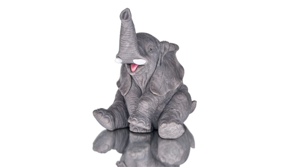 An 11.8-centimeter carving of an elephant in dark gray obsidian, with a rhodonite tongue, cacholong tusks, and black onyx eyes image