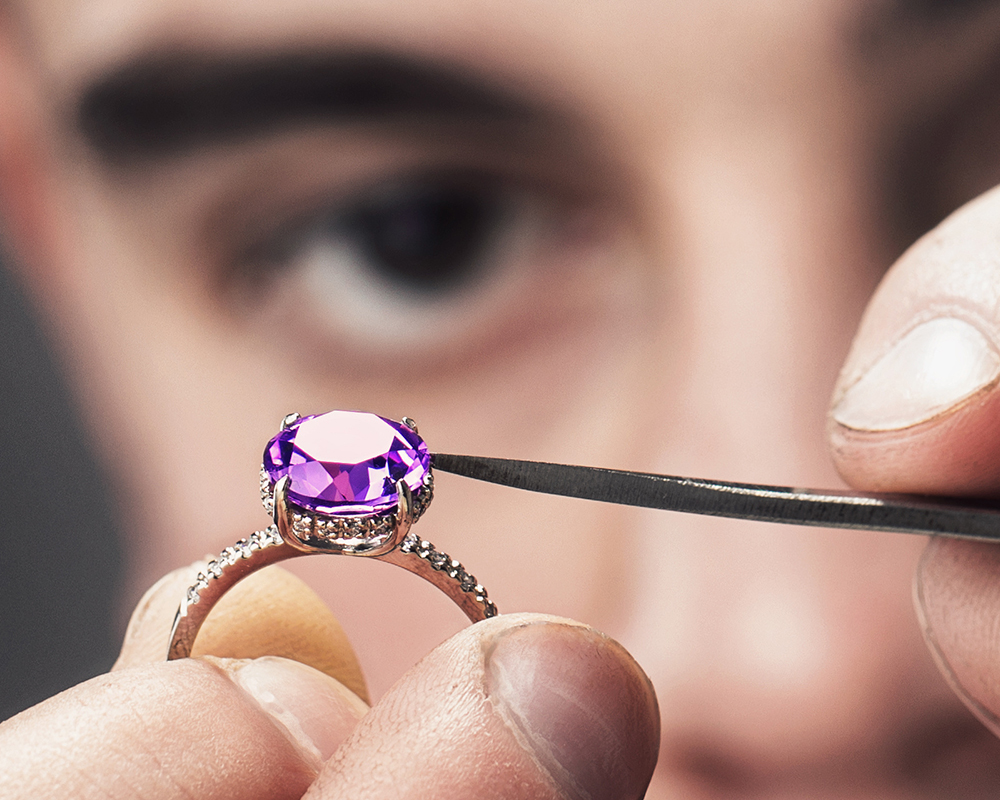 Jeweler examining an amethyst gem set in an engagement ring image