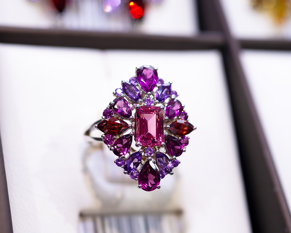 Showcase displaying white gold ring with amethysts, rubies, and tourmalines image