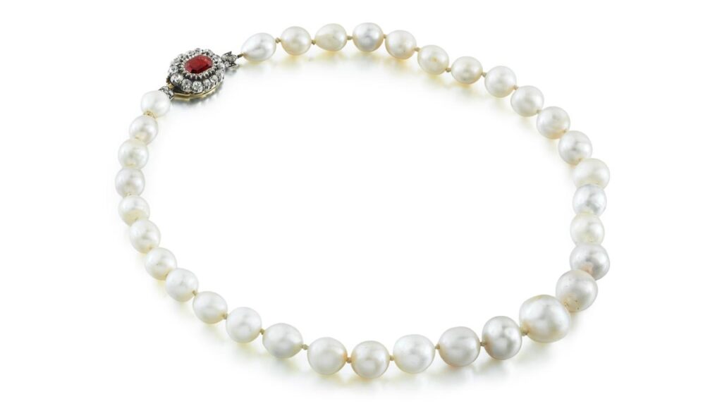 A necklace comprising 33 rounded, oval, button- and drop-shaped natural pearls, with a clasp bearing an octagonal rhodolite garnet and circular-cut diamonds at Sotheby's image