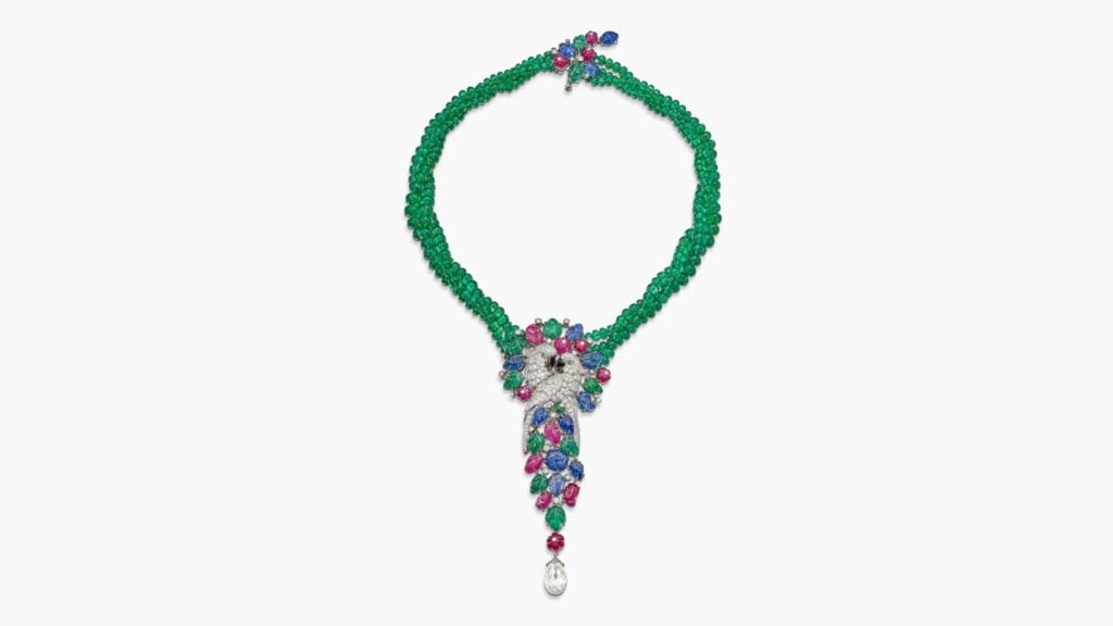 A Cartier tutti frutti pendant necklace designed as a pair of embracing parrots. It comprises brilliant-cut diamonds, emeralds, sapphires, rubies, and mother of pearl, and suspends a diamond briolette by Sotheby's image