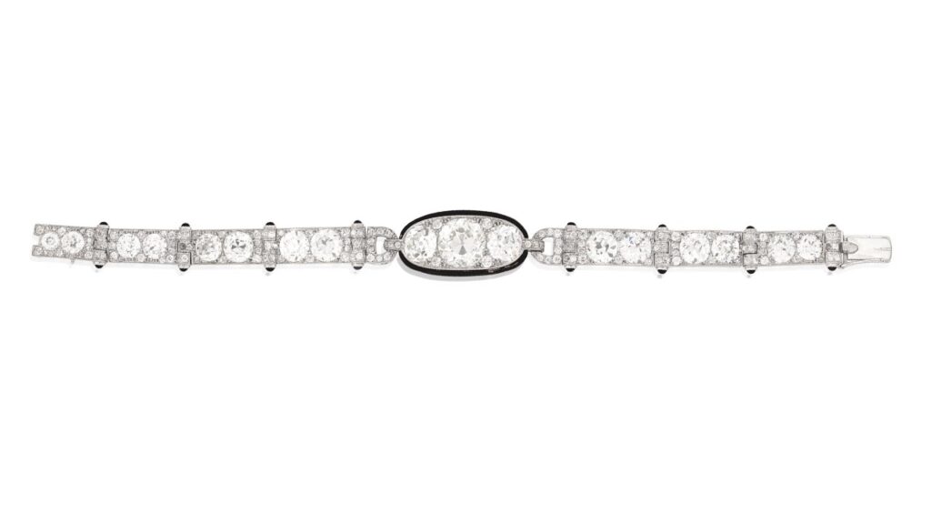 A Cartier bracelet from 1925 centers an old brilliant-cut, 5.82-carat diamond between two old brilliant-cut diamonsd, each link with millegrain detailing and black enamel terminals. The strap comprises old brilliant-cut diamonds at Bonhams image