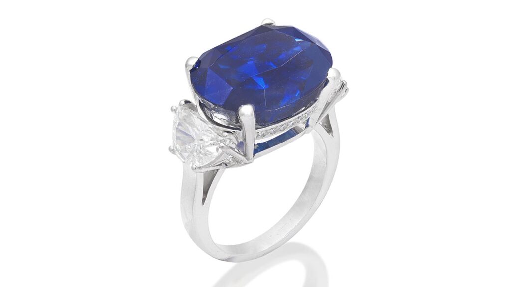 An Aldao ring bearing an oval-cut, 14.65-carat Burmese sapphire between demi-lune-cut diamonds. The gallery is pavé-set with brilliant-cut diamonds at Bonhams image