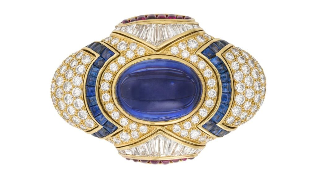A Bulgari clip-brooch centers an oval-shaped cabochon, 29.92-carat star Ceylon sapphire, with a surround of buff-top rubies and sapphires, and round, tapered baguette and baguette-cut diamonds at Christie's image