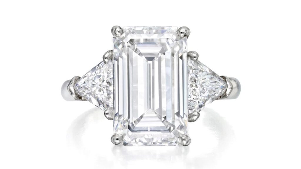 A ring centering a step-cut, 5.29-carat, D, VS1 diamond between two triangular stones at Phillips image