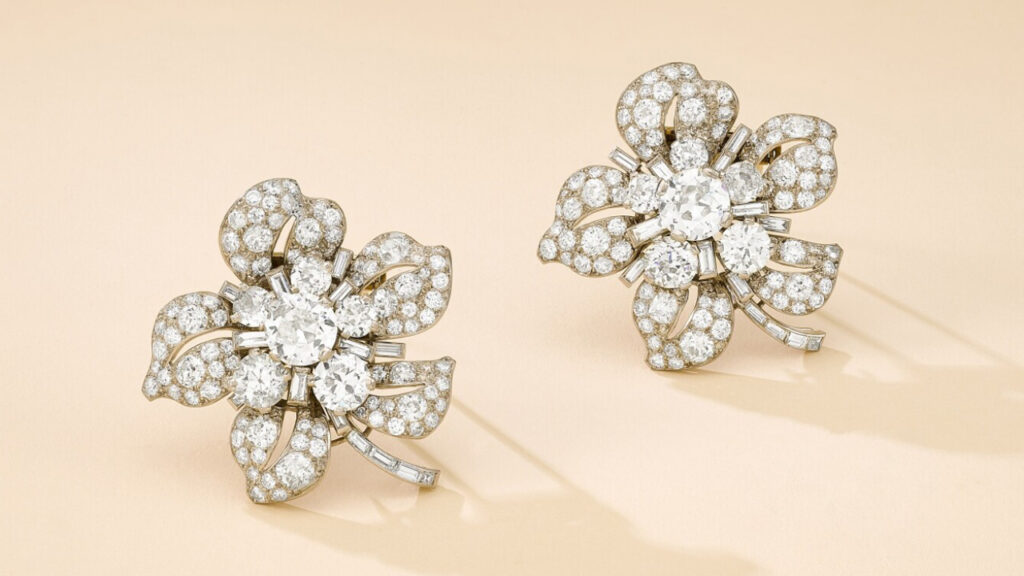 A pair of Monture Cartier brooches from around 1935 designed as flowerheads, each featuring an old brilliant-cut diamond cluster center, surrounded by similarly set pierced petals, on a baguette-cut diamond stem at Sotheby's image