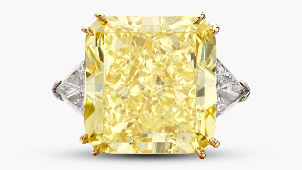 A ring with a round cornered square modified brilliant-cut, 34.75-carat, fancy-intense-yellow, VS1 diamond between by two triangle-shaped diamonds at Sotheby's image