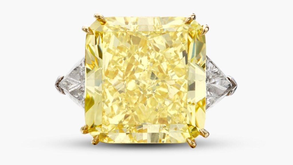 A ring centering a round cornered square modified brilliant-cut, 34.75-carat, fancy-intense-yellow, VS1 diamond between a pair of triangle-shaped diamonds at Sotheby's image
