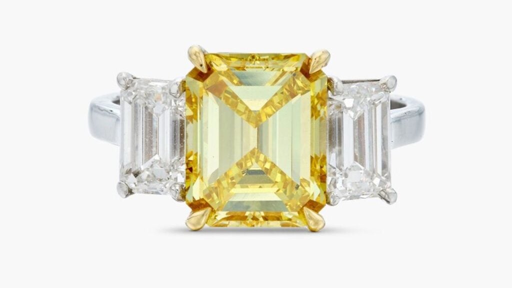 A ring centering an emerald-cut, 4.20-carat, fancy-vivid-yellow, VVS2-clarity diamond between two emerald-cut diamonds of 1.07 and 1.08 carats at Sotheby's image