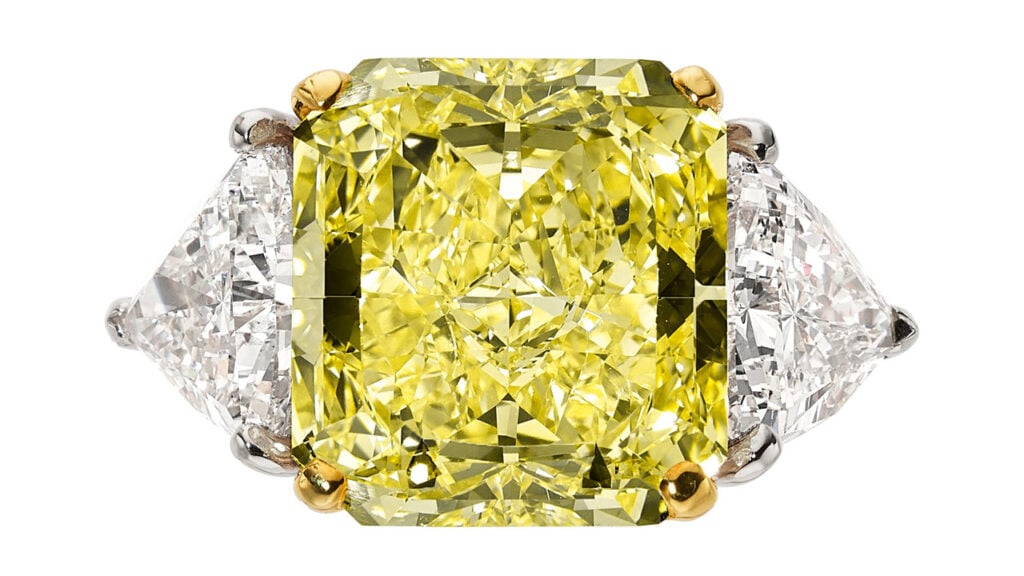 An Oscar Heyman ring bears a rectangular-shaped, 14.11-carat, fancy-yellow, VVS2 diamond between two triangular stones weighing 2.09 and 2.24 carats at Heritage Auctions image