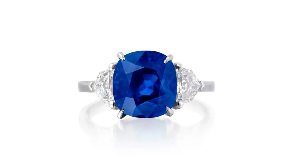 A ring features a cushion-shaped, 6.07-carat Burmese sapphire between two shield-shaped diamonds at Phillips image
