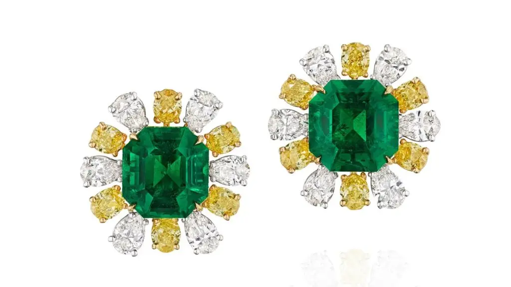 A pair of ear clips comprises emerald-cut Colombian emeralds weighing 5.15 and 5.59 carats, framed by alternating oval-shaped diamonds with a yellow tint and pear-shaped diamonds at Bonhams image