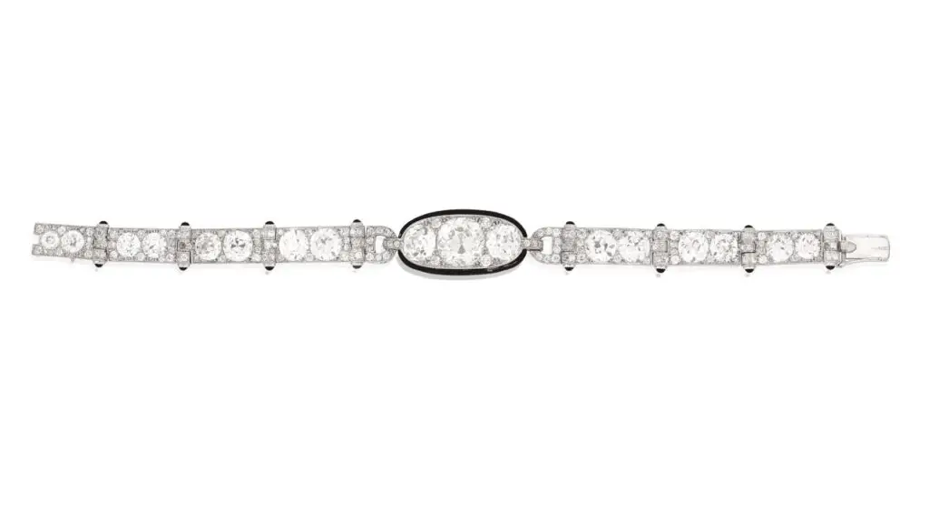 A Cartier bracelet from 1925 centers an old brilliant-cut, 5.82-carat diamond between two old brilliant-cut diamonsd, each link with millegrain detailing and black enamel terminals. The strap comprises old brilliant-cut diamonds at Bonhams image