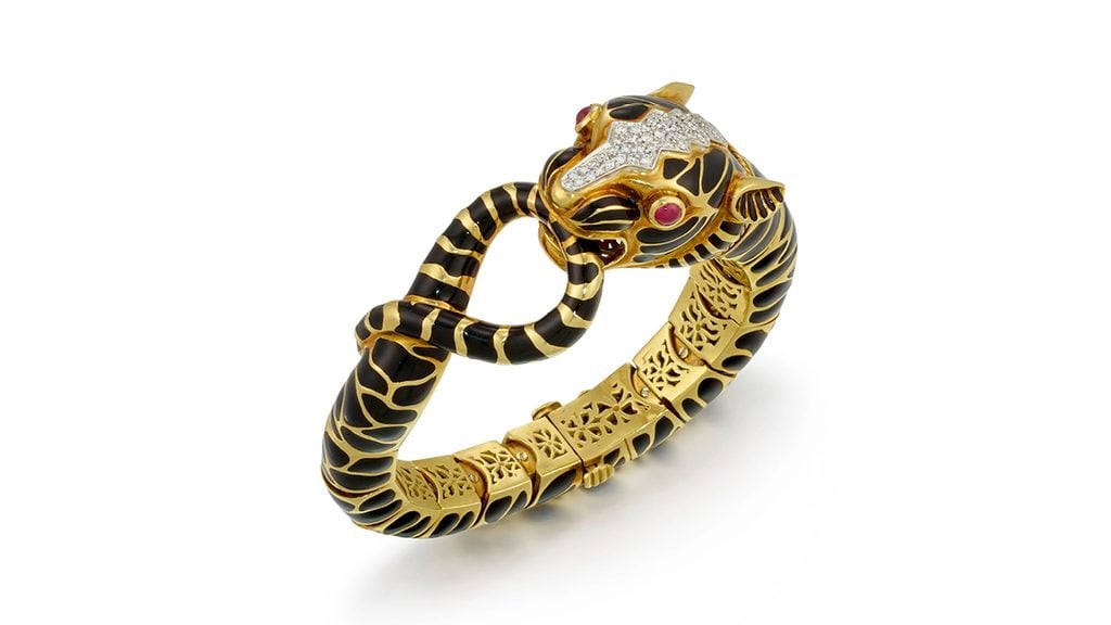 A David Webb bangle designed as a panther clasping its tail features a black enamel body and a head and collar accented with more than 70 round brilliant-cut diamonds totaling 1.10 carats, with round cabochon rubies as eyes at Bonhams image