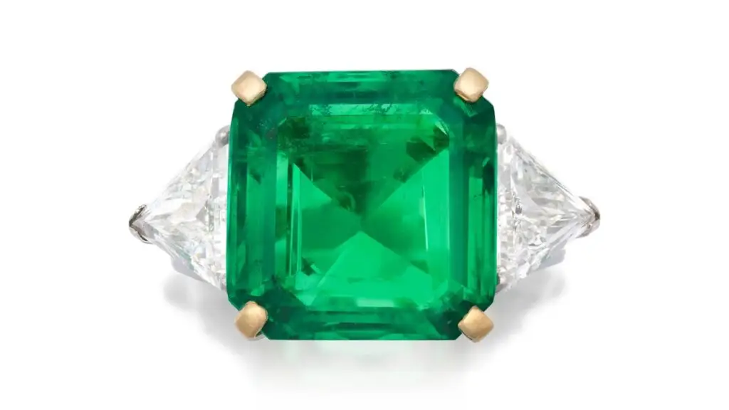 This ring bears an octagonal step-cut, 9.13-carat Colombian emerald flanked by two trilliant-cut diamonds. at Bonhams image