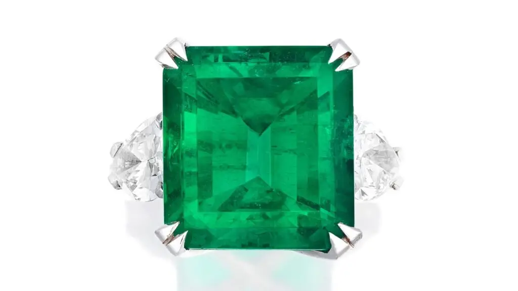A ring bearing a step-cut, 20.56-carat Colombian emerald between pear-cut diamond shoulders at Bonhams image