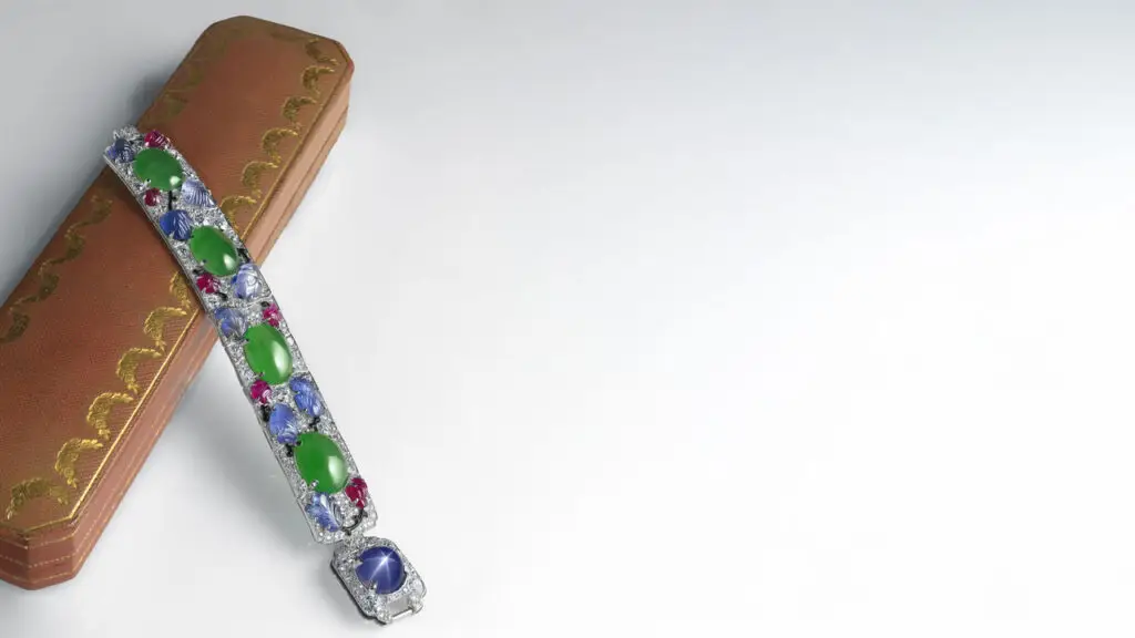 This Art Deco style multi-gem bracelet by Cartier from around 1925 contains jadeite cabochons, cabochon star sapphire, carved rubies and sapphires, black enamel, and old- and single-cut diamonds at Christie's image