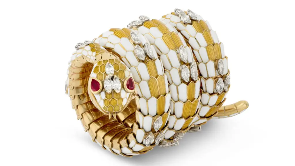 This Bulgari bracelet-watch is designed as a serpent. It bears yellow and white enamel, marquise-shaped diamonds, and pear-shaped rubies as eyes at Christie's image