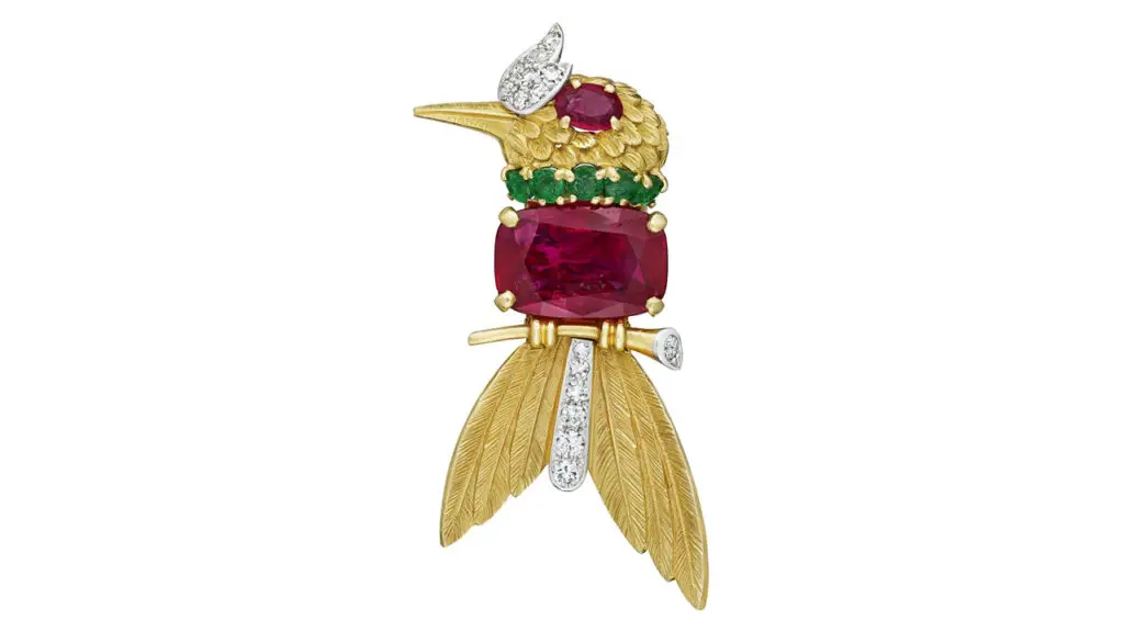 A Cartier brooch designed as a bird on a branch. It sports a cushion mixed-cut Burmese ruby weighing 6.26 carats as well as an oval-shaped ruby, round emeralds, and round and single-cut diamonds at Christie's image