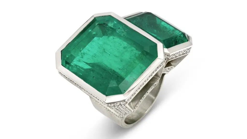 A ring bearing two octagonal-shaped Colombian emeralds weighing around 50 and 18 carats, with round diamonds on the band at Christie's image