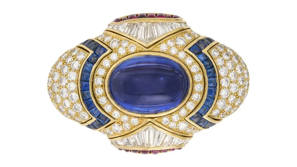 A Bulgari clip-brooch centers an oval-shaped cabochon, 29.92-carat star Ceylon sapphire, with a surround of buff-top rubies and sapphires, and round, tapered baguette and baguette-cut diamonds at Christie's image