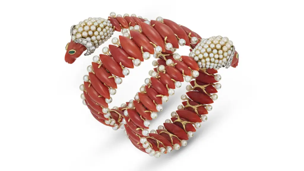 Cartier made this coral, pearl, diamond and emerald bangle in the 1950s. Featuring a ram’s head at both ends at Christie's image