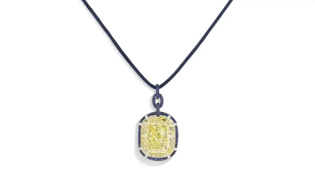 A pendant bearing a cushion-shaped, 100.40-carat, fancy-intense-yellow, SI2 diamond within a border of round sapphires at Christie's image