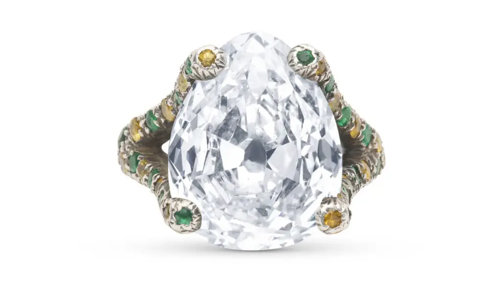 A pear-shaped modified brilliant-cut, 9.45-carat, I, SI2 diamond is the highlight of this ring, with added round emeralds and colored sapphires on the band at Christie's image
