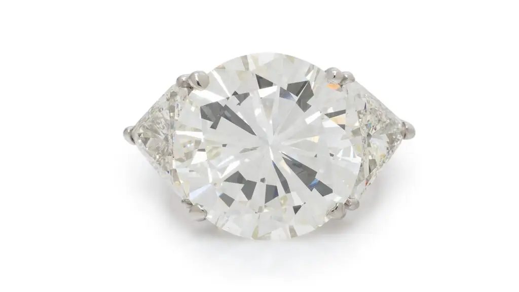 A round,12.32-carat, L, VS2 diamond is the highlight of this ring, sitting between a pair of trillion-cut diamonds at Freeman's image