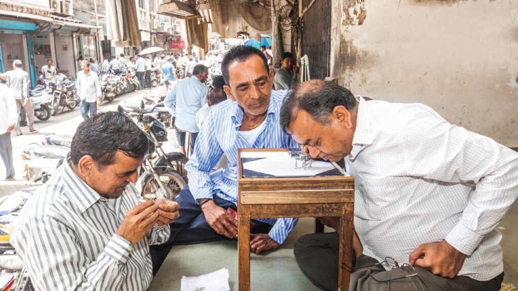 Diamond dealers examine stones in Surat image