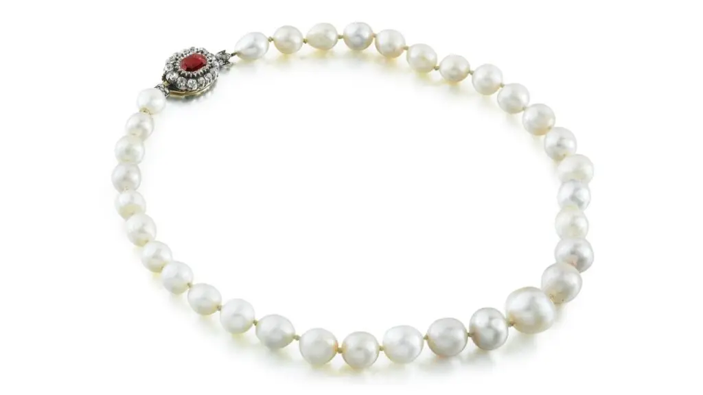 A necklace comprising 33 rounded, oval, button- and drop-shaped natural pearls, with a clasp bearing an octagonal rhodolite garnet and circular-cut diamonds at Sotheby's image