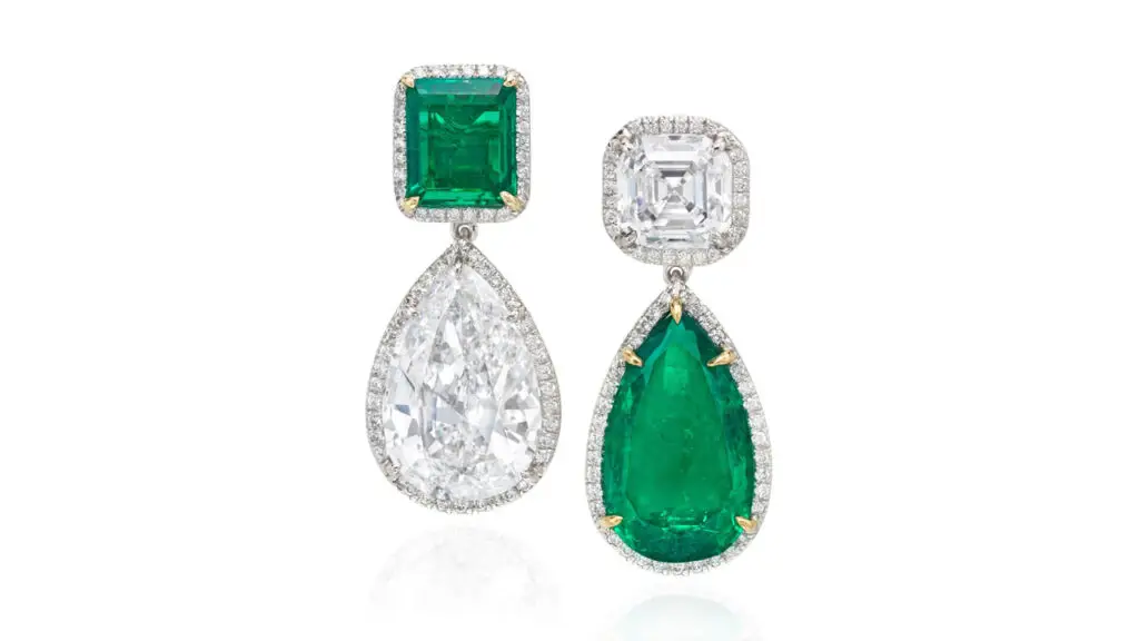 A pair of emerald and diamond earrings. One has a step-cut, 3.01-carat, D, VS1 diamond suspending a pear-shaped, 6.44-carat Colombian emerald, and the other features a step-cut, 1.93-carat Colombian emerald suspending a pear-shaped, 7.45-carat, E, VS1 diamond. Each is in a circular-cut diamond frame at Phillips image