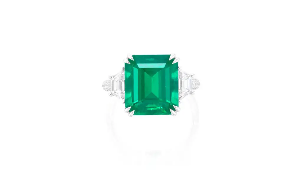 This ring contains a step-cut, 7.15-carat Colombian emerald between two trapeze-cut diamonds image