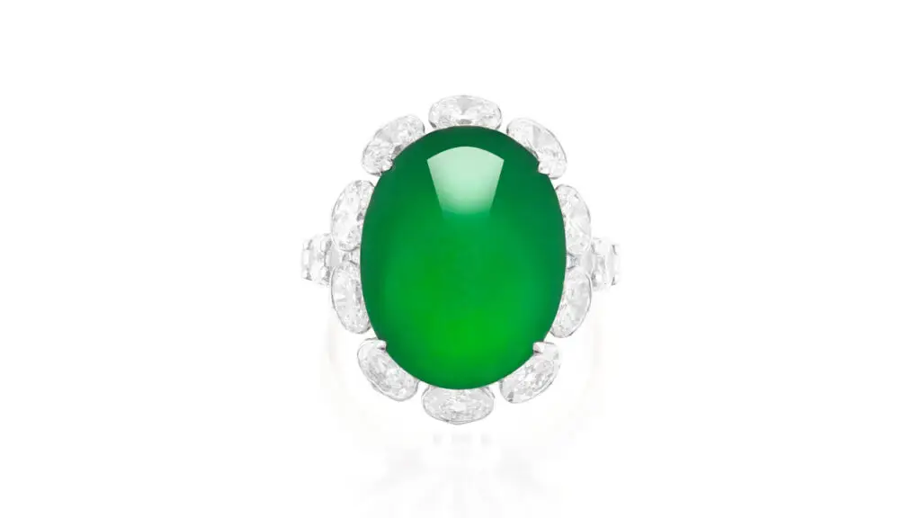 A ring centering a translucent oval jadeite cabochon in an oval-diamond surround and with brilliant-cut diamond shoulders image