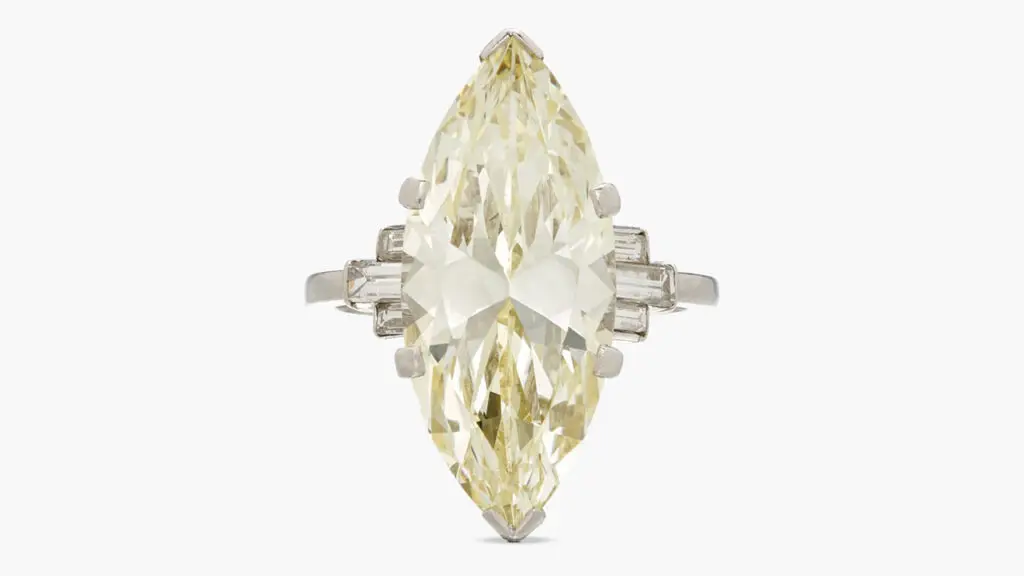 A ring with a marquise-shaped, 9.19-carat, fancy-yellow, VS1 diamond, between baguette diamonds at Sotheby's image