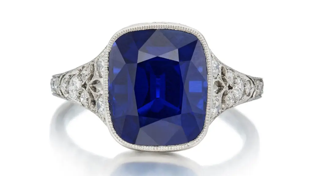 This Tiffany & Co. ring bears a cushion-shaped, 5.61-carat Kashmir sapphire, with round-diamond accents and fleur-de-lis motifs on the shoulders at Sotheby's image