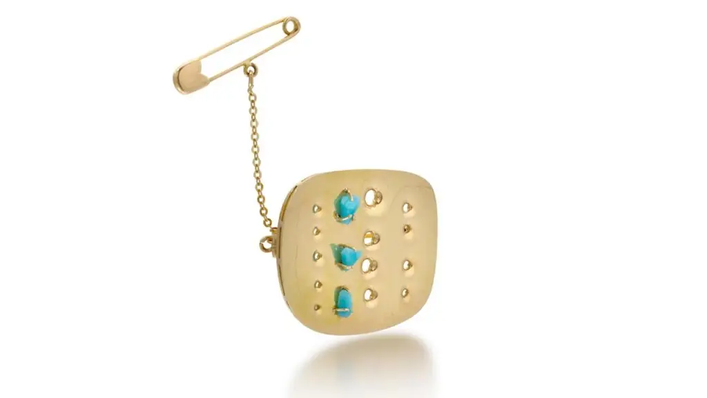 This Lucio Fontana gold Concetto Spaziale brooch has a geometrical design with distinctive holes, decorated with turquoise vitrum pastae at Sotheby's image