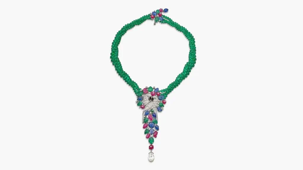 A Cartier tutti frutti pendant necklace designed as a pair of embracing parrots. It comprises brilliant-cut diamonds, emeralds, sapphires, rubies, and mother of pearl, and suspends a diamond briolette by Sotheby's image