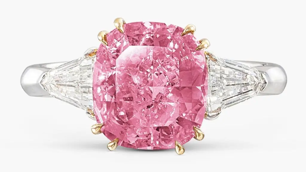 A ring with a cushion-shaped, 2.86-carat, fancy-vivid-purplish-pink, I2 diamond between two shield-shaped diamonds Sotheby's image